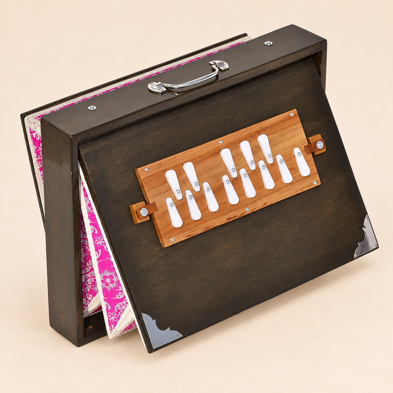 Oak-finish shruti box with magenta floral bellows open, left angle on warm sand background