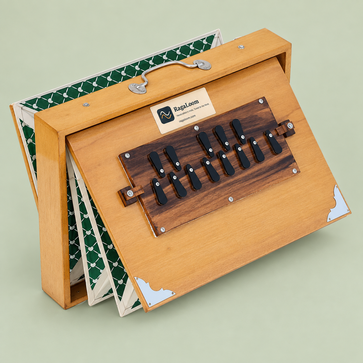 Natural teak-finish shruti box with green patterned bellows open, left angle on soft sage background
