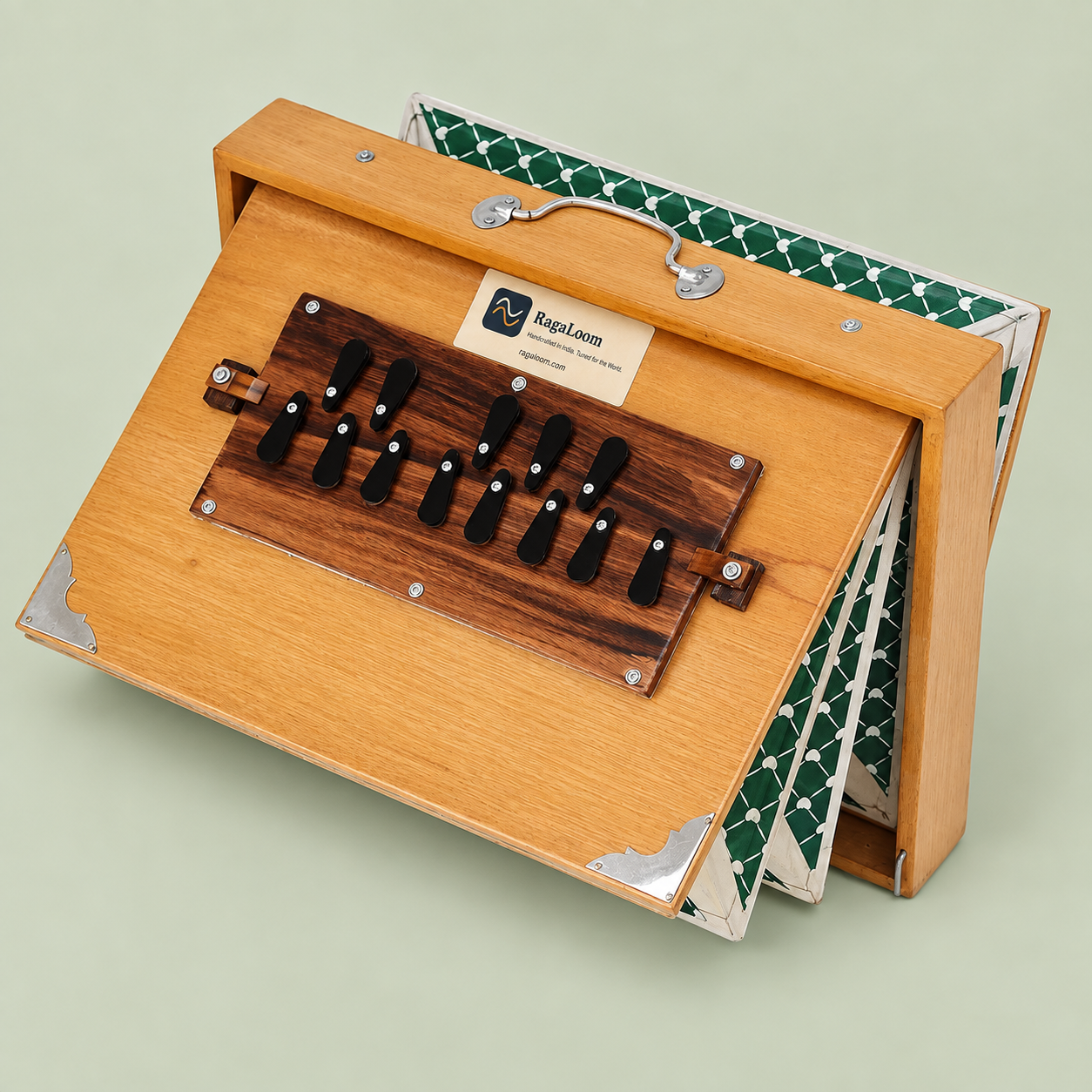 Natural teak-finish shruti box with green patterned bellows open, right angle on soft sage background
