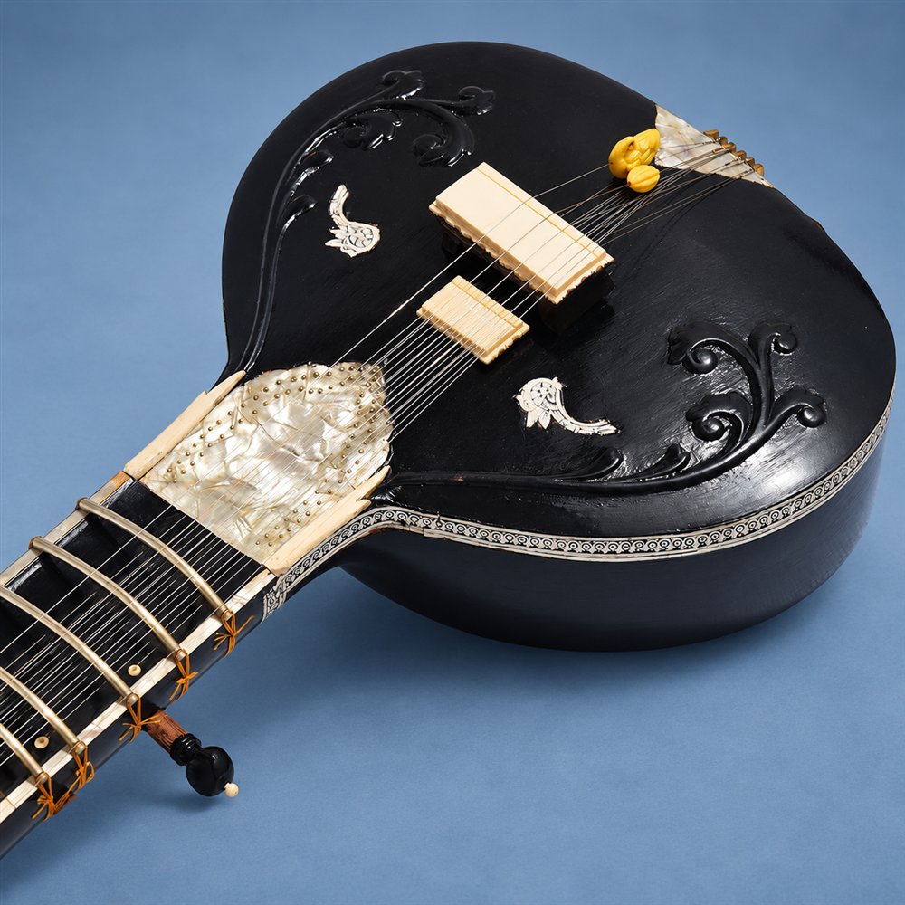 Black flat-back sitar body with bridge and decorative inlay
