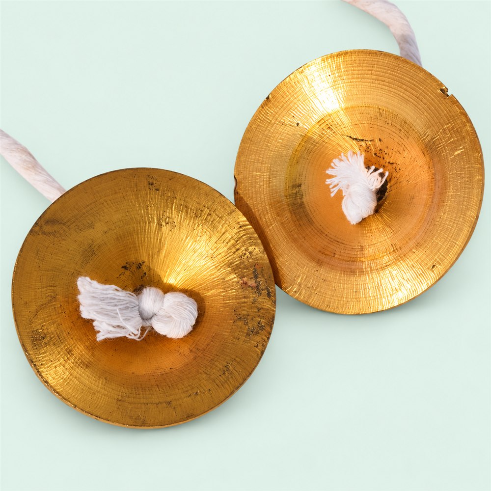 Separated brass manjira hand cymbals with white holding cords